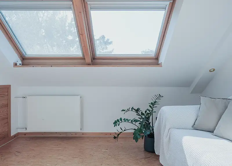 Helles Dachzimmer mit großen Fenstern und Pflanze